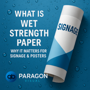 Rolled-up poster labeled “Signage” on a blue waterdrop-textured background with bold white text reading “What is Wet Strength Paper – Why It Matters for Signage & Posters.”