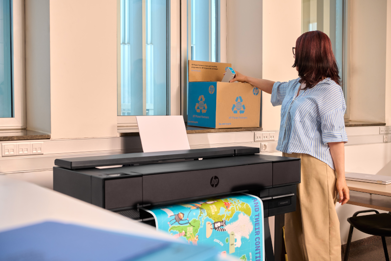 HP DesignJet T870 printer in a classroom while a staff member scans an HP recycling box